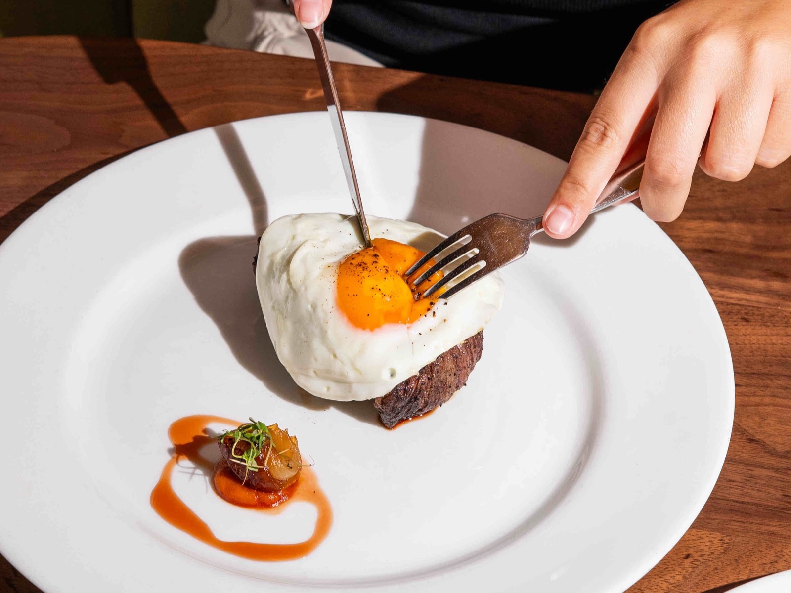 The Arthur J steak and eggs — a wood-fired premium cut with a sunny-side-up organic egg