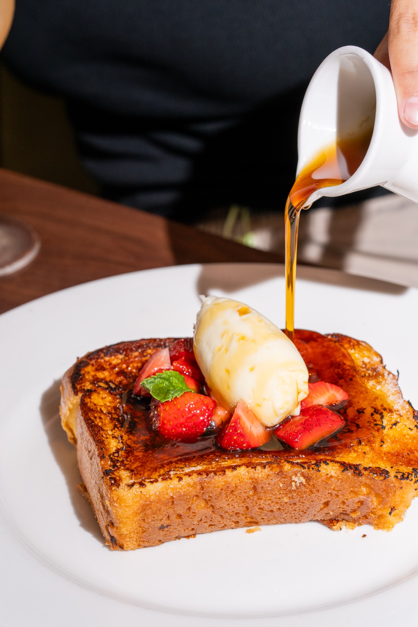 Hot buttered-maple syrup poured over bruleed brioche French toast with strawberries and whipped mascarpone at brunch