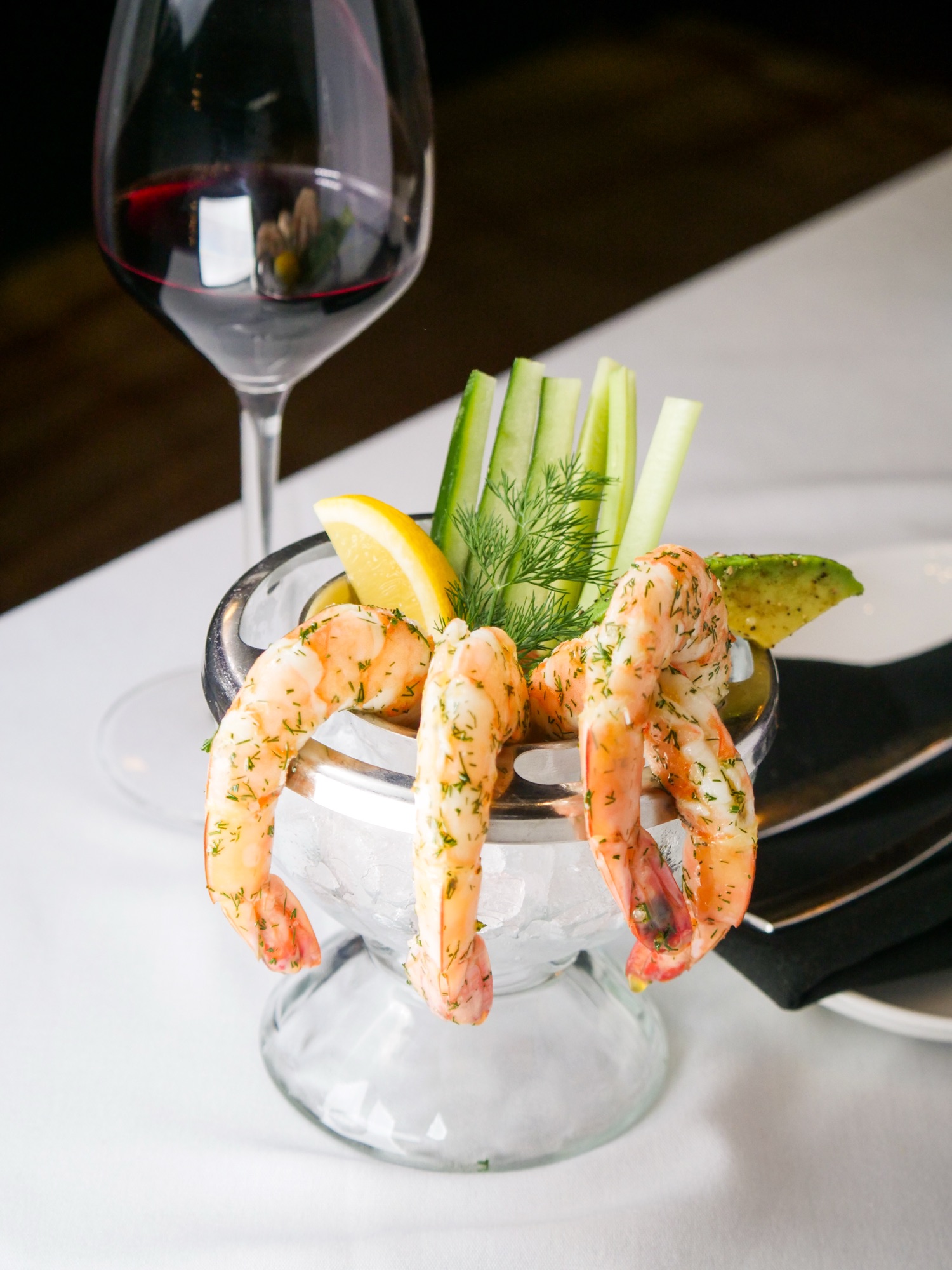 Chilled jumbo shrimp cocktail served in a glass over ice with spicy cocktail sauce